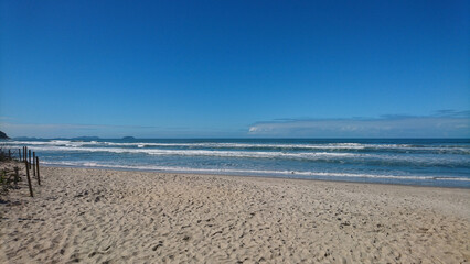 Calm sea with gentle waves, clean beach and light blue sky