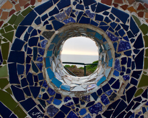 mosaic in the wall with a hole looking through to see the water 