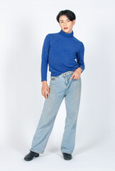 Fototapeta na wymiar Portrait isolated cutout studio full body shot of Asian young gay male model in turtleneck longsleeve shirt denim jeans with high heel leather shoes standing posing look at camera on white background