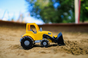 Toy excavator in the children's sandbox. Background with selective focus