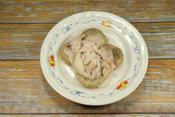 Pile of steamed coconut dumpling dressing with fresh sliced coconut meat serving on the plate. Famous traditional sweet dessert in Asia. 