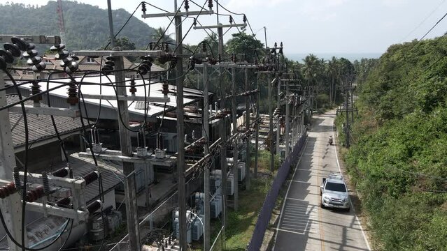 Motorbike and car driving on a road close to an electric power plant in koh tao
