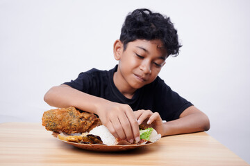 Little Boy eating Fried Fish and rice at home