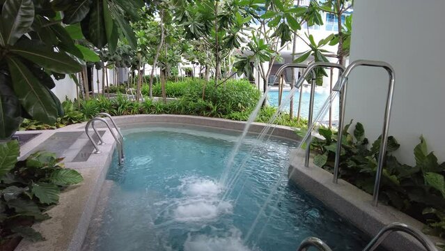 Jacuzzi water tap flow in pool of green lush environment