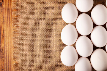 White chicken eggs arranged on burlap texture. Very popular nutritious and economic food product. Top table view. Cop space.