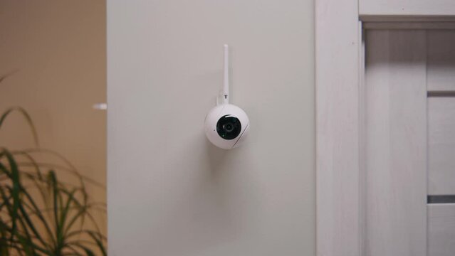 Zoom out of installed security camera on the wall in the modern apartment. CCTV camera with microphone and motion sensor. Concept of tracking system, surveillance, safety and personal privacy.