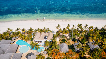This drone shot of Zanzibar's beach is a tropical paradise with palm trees, white sand, and...