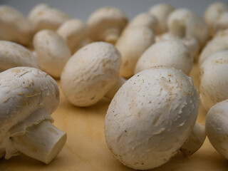 Fresh champignon mushrooms on wooden table, closeup.
Mushrooms are like vegetable protein. The concept of vegetarian and vegan food and diet. Veganism and vegetarianism. Cooking at home.