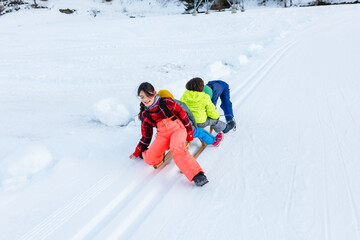 group of children finished riding one wooden sled down snow slope playing together