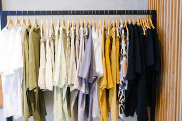 Two Racks of summer collection of natural clothes on hangers in retail fashion shop.