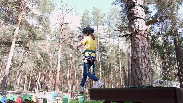 Holidays. A happy child, a girl in a helmet, spends active time in a climbing adventure park on a summer day