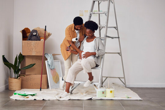 Painting, pregnancy or home with a black couple in DIY, renovation or house remodel with a paintbrush or roller. Teamwork, partners or African man and pregnant woman excited about baby or new family