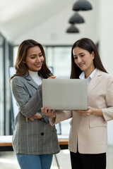 Beautiful Asian businesswoman standing holding laptop Consultation for business planning financial budget Marketing to analyze customer groups to increase the amount of growth of the company.