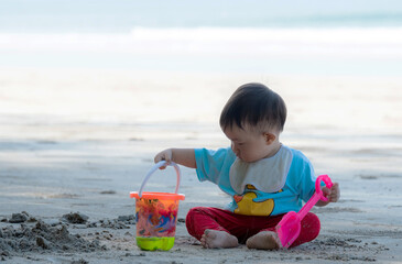 Baby boy playing in sand on a tropical beach