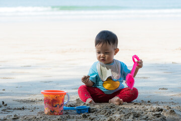 Baby boy playing in sand on a tropical beach
