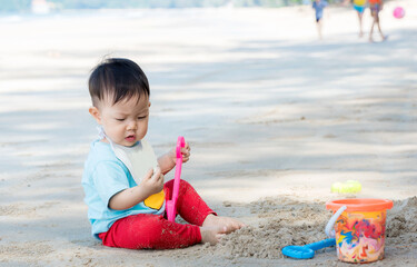 Baby boy playing in sand on a tropical beach