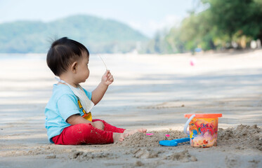 Baby boy playing in sand on a tropical beach