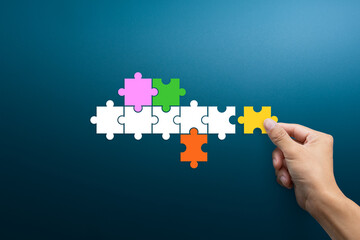 Hand connecting puzzle pieces representing Joint venture, Partnership, Mergers and acquisition concept.