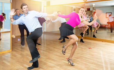 Spirited middle-aged pair training Latino dance during workout session. Pairs training ballroom...