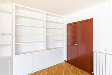 Large wooden closed mahogany door with a brass handle for opening. Along the wall is a white open...