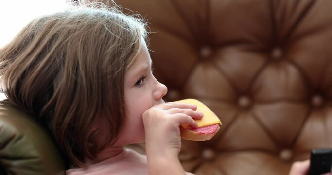 Little girl child eats cheese and sausage sandwich and long loaf