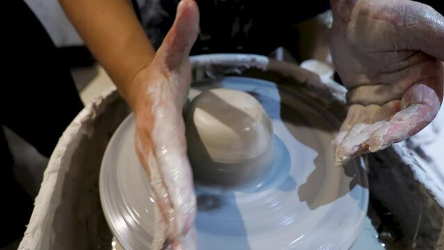 side  view of an African American hands spinning clay very sporadically while the wet molded clay moves violently through the fingers