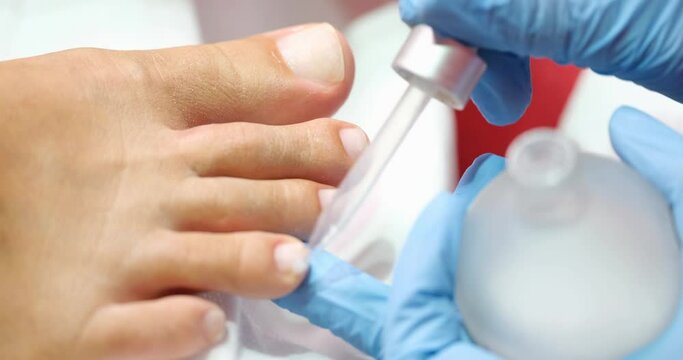 Manicurist apply oil on cuticles of toes