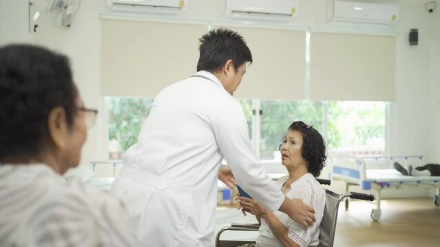 An Asian doctor with a group of old elderly patient or pensioner in nursing home in hospital. Senior people lifestyle activity recreation. Health care physical therapy.