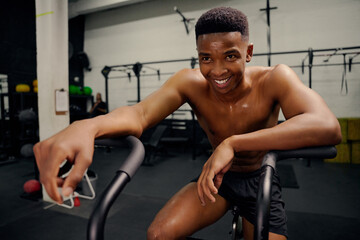 African American male using an elliptical trainer during cross fit training. Male athlete...