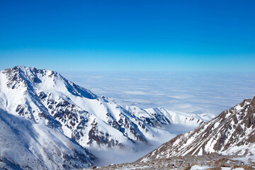 Naklejka premium Beautiful landscape of winter mountains over clouds.