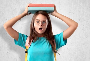 Cute small scared school child for holds book on head.