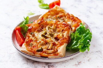 Children mini pizza , small open pies with ham, tomato sauce, mozzarella and cheese in basket on a light background.