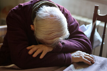 White-haired old man or grandfather sleeping or resting on a table. Concept of social problems,...