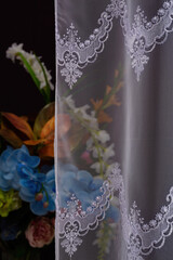 Beautiful tulle or transparent curtain with a pattern on a dark background.