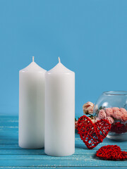 Two white candles on a blue wooden table