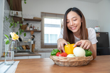 Obraz premium Panoramic shot of Asian woman in healthy apron preparing and holding chilli vegetables In the kitchen at home before cooking online smiling happily at the camera to stay healthy safe from disease.