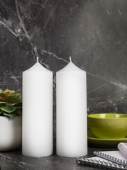 Two white candles on a dark marble table