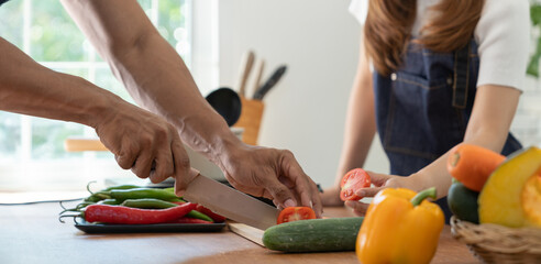 Image of Asian couple doing activities together by cooking learning how to do it online happily with healthy vegetable ingredients in their own homes, people-to-people concept and online education.