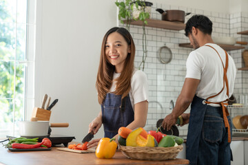 Image of Asian couple doing activities together by cooking learning how to do it online happily with healthy vegetable ingredients in their own homes, people-to-people concept and online education.