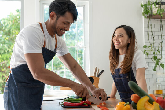 Image of Asian couple doing activities together by cooking learning how to do it online happily with healthy vegetable ingredients in their own homes, people-to-people concept and online education.