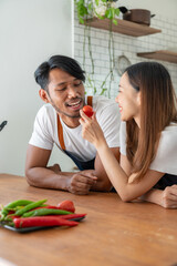 Image of a couple cooking in the kitchen Young men and women having fun together while testing tomatoes and other ingredients to learn how to make different dishes online healthy living concept.