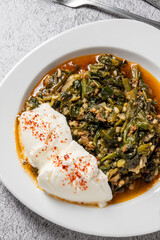 Traditional Turkish spinach meal with rice and minced meat with yogurt on a white porcelain plate