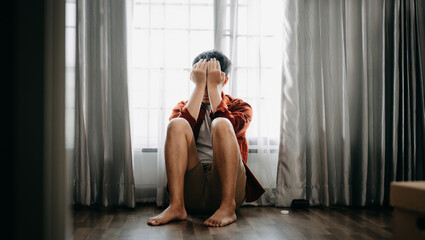 Fototapeta premium Asian Man sit Depression Dark haired pensive glance Standing by window and anxiety Copy space.