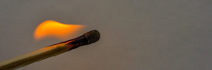 Macro shot of a wooden safety matchstick burning with a bright colorful flame.