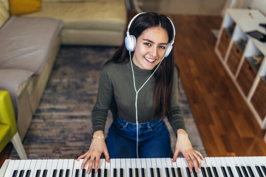 Happy girl is playing piano for her hobby relax time in home living room. Portrait Of Smiling Teenage Girl At Home Playing The Piano