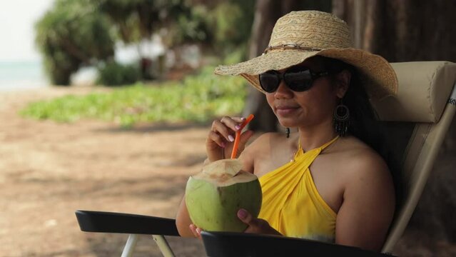 Image Of A Woman Relaxing Near The Beach While Drinking Fresh Coconut Juice. Close Up