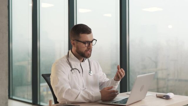 Close-up portrait of a male doctor conducting an online consultation on a laptop