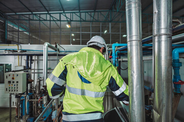 Caucasian technician engineer man in safety uniform standing with pipeline, boiler tank in beverage processing laboratory plant