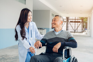 Obraz premium Asian young doctor taking care and talking mature female patient sitting on wheelchair in hospital. Healthcare concept.
