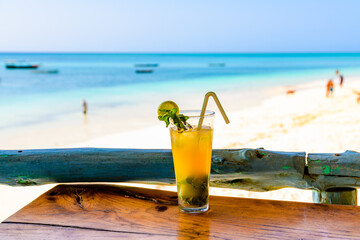 Glass of orange mojito cocktail. Ocean at the background